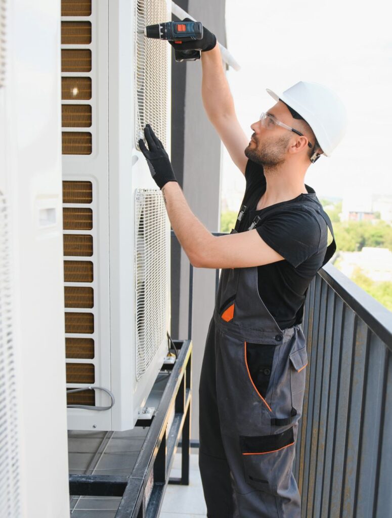 Technician performing AC repairs on outdoor unit, ensuring efficient airflow and system compliance for improved indoor air quality.