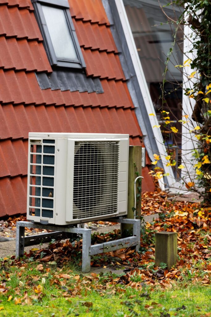 HVAC outdoor unit installed on a grassy area with fallen leaves, emphasizing eco-friendly installation practices for improved energy efficiency and reduced environmental impact.