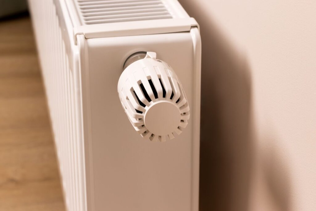 Furnace radiator with a white thermostat knob, illustrating HVAC system maintenance and efficiency for cleaner air and optimal performance.