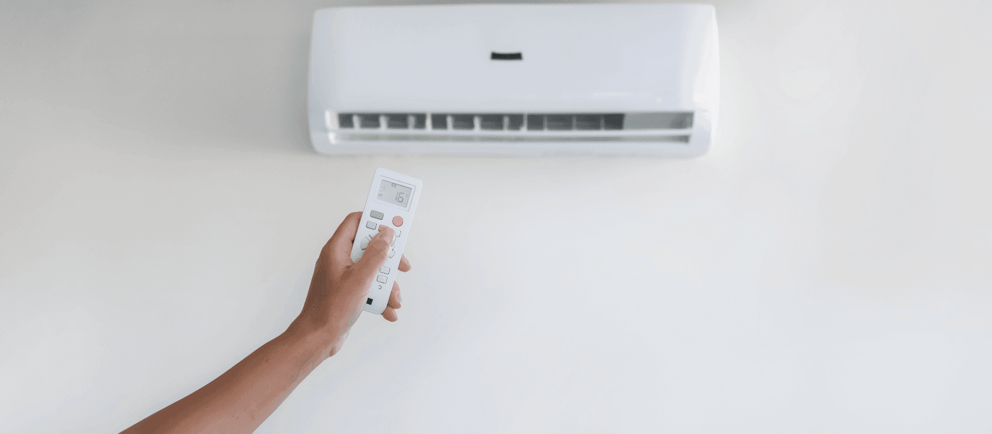 Person operating heat pump remote control to set energy-efficient heating and cooling