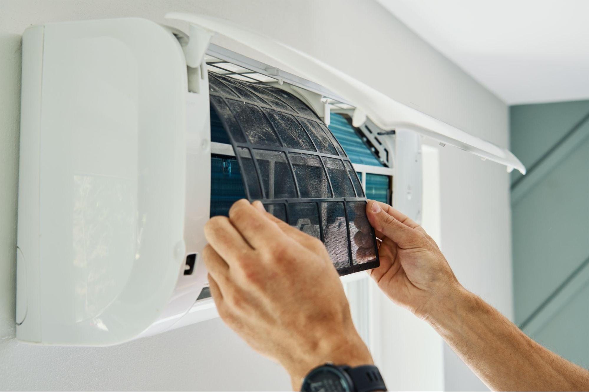 Technician removing a dirty air filter from a heat pump during maintenance in Macomb, MI