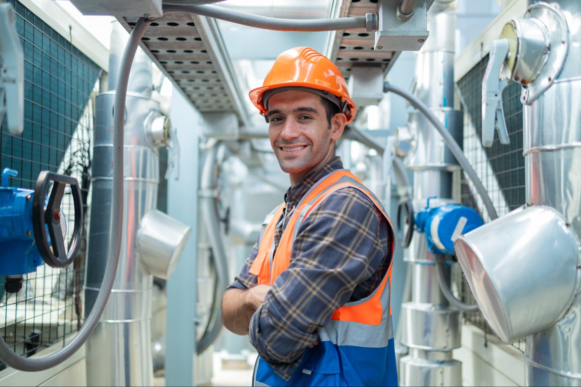HVAC technician in orange safety vest inspecting rooftop cooling equipment in St. Clair County, MI