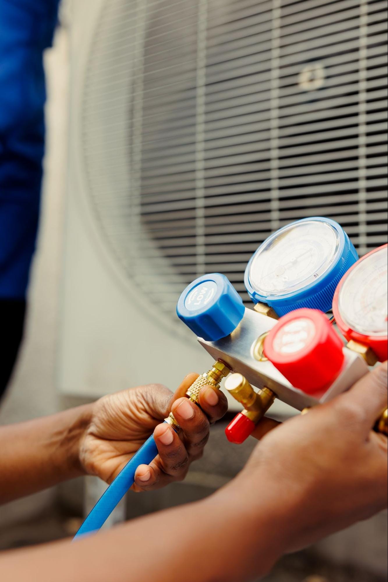 Close-up of HVAC technician checking refrigerant pressure gauges on an air conditioning unit in Clay Township, MI