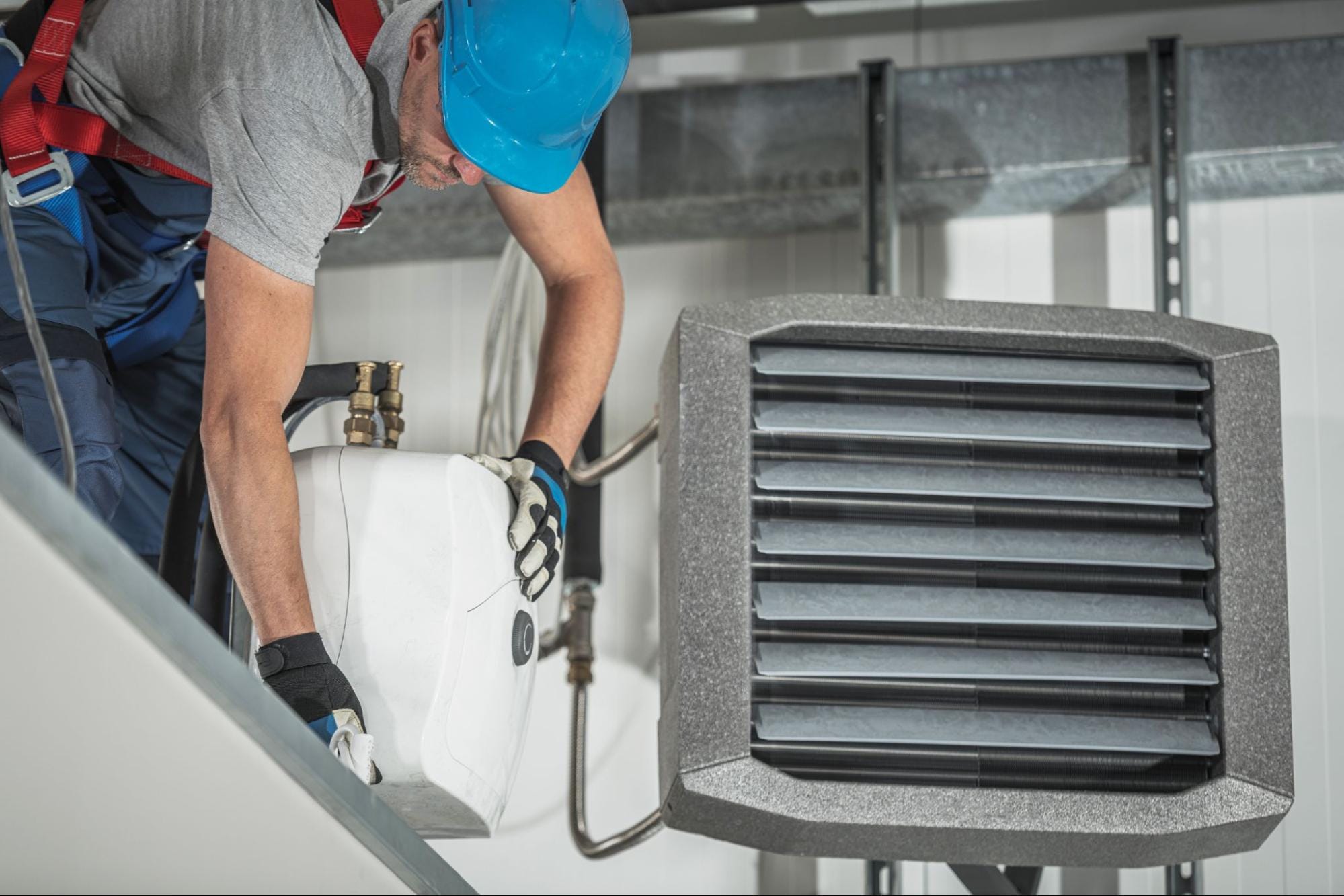 HVAC technician in safety gear installing a commercial heat pump unit