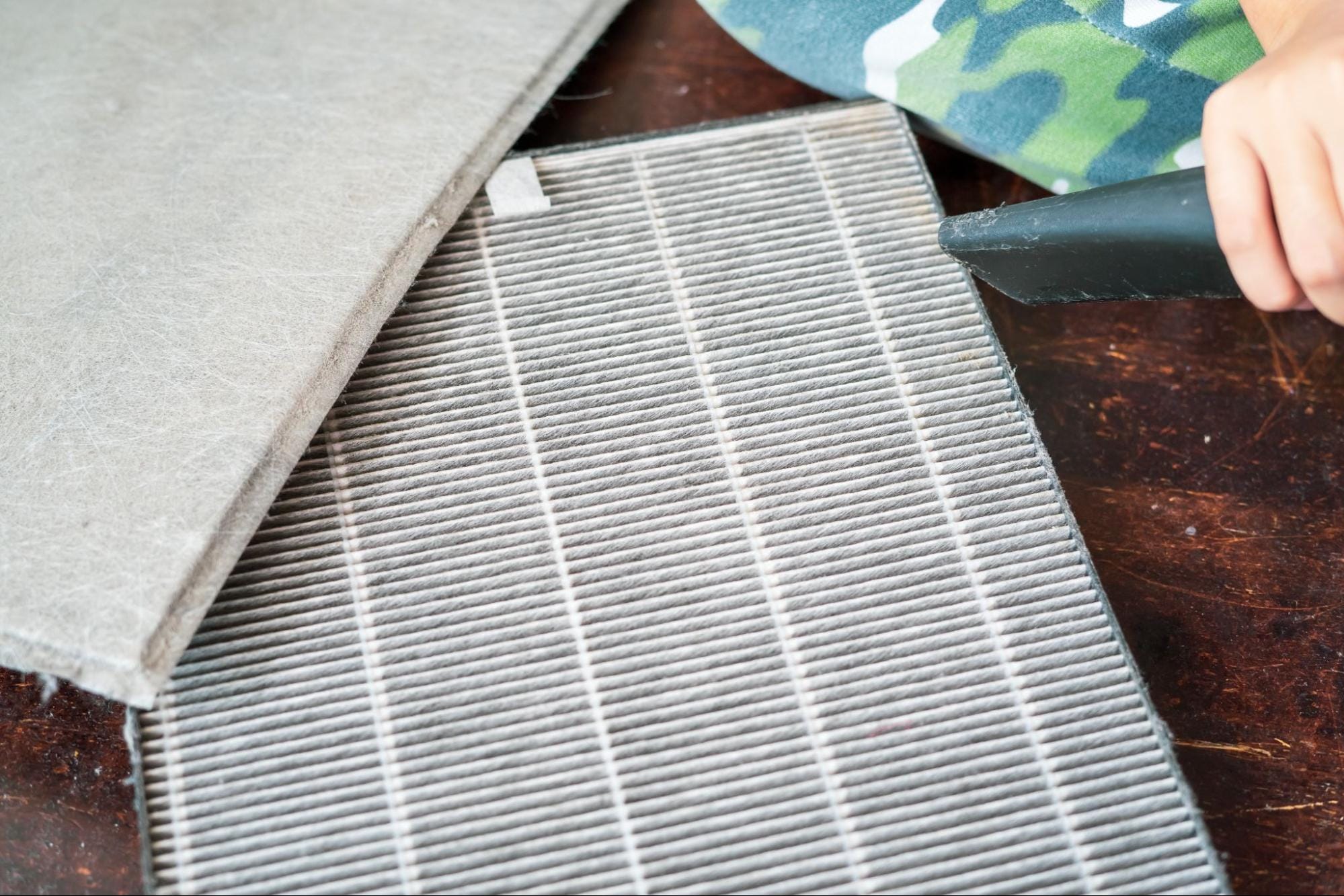Close-up of a dusty HVAC filter being vacuumed during routine maintenance