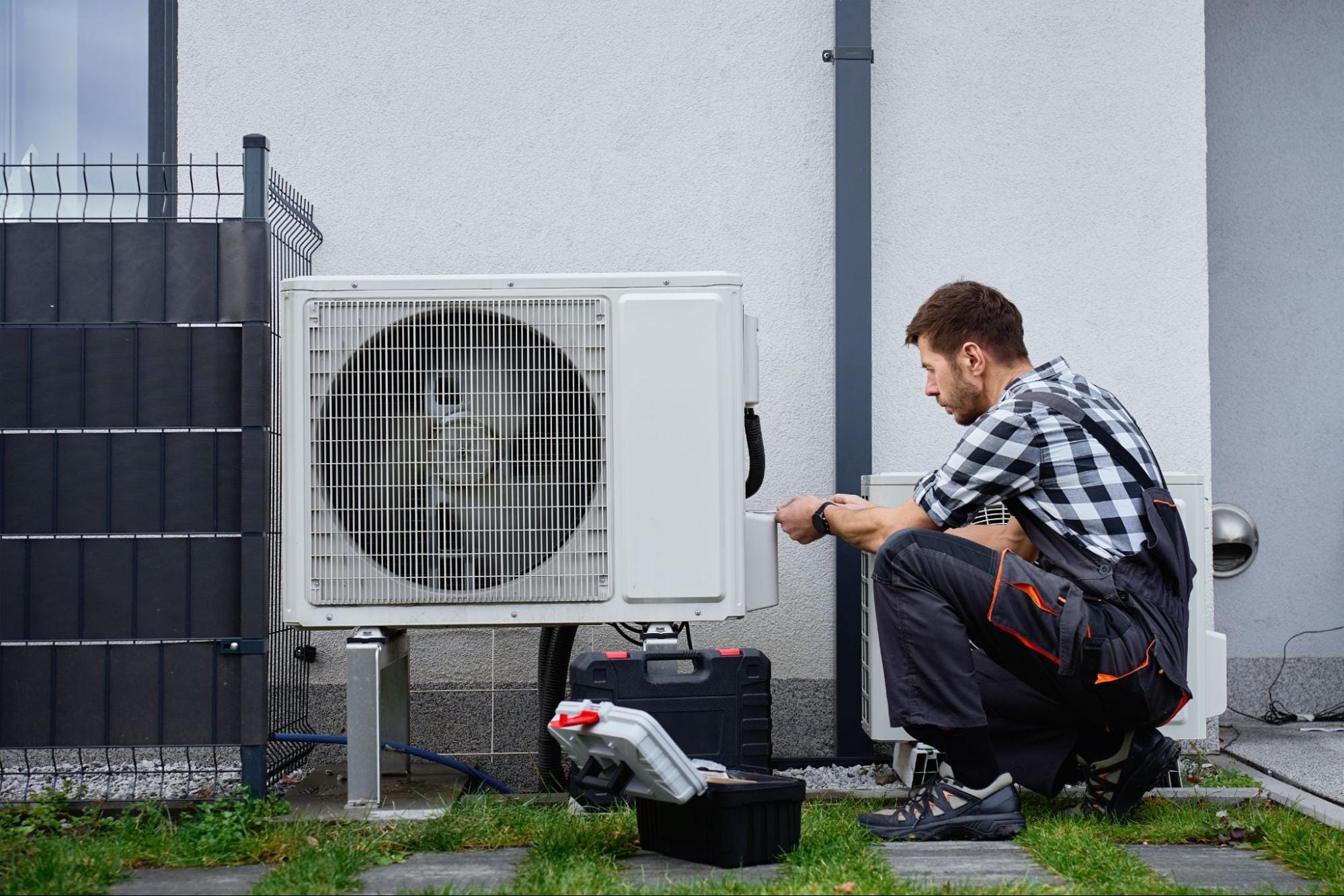 HVAC technician repairing a residential heat pump unit outside a home in Clay Township, MI