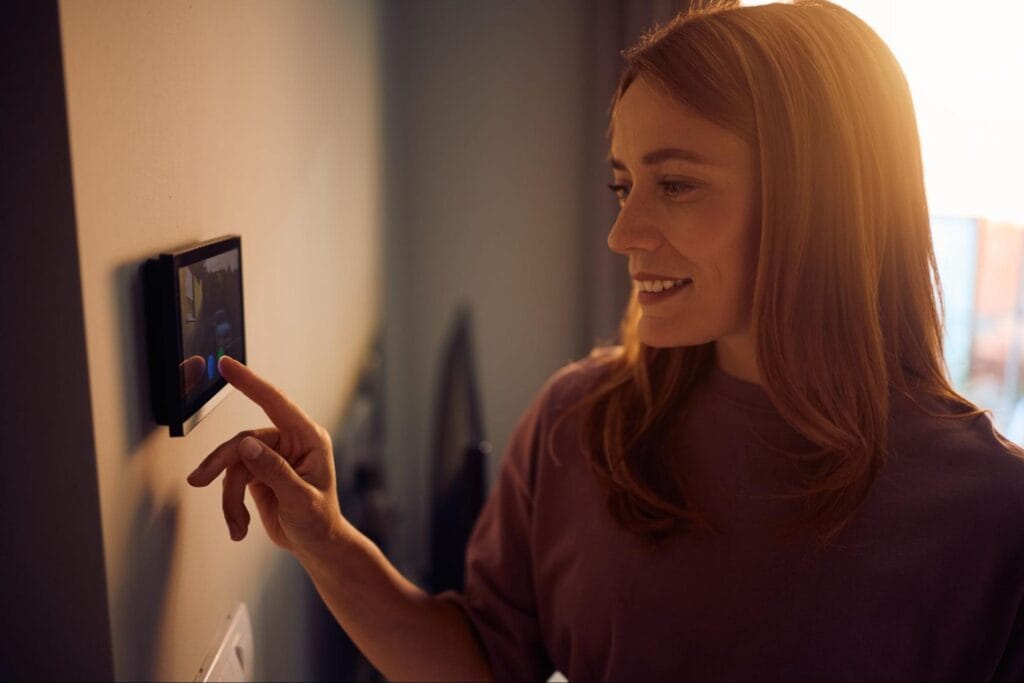 Woman adjusting a smart thermostat touchscreen on the wall in Clay Township, MI