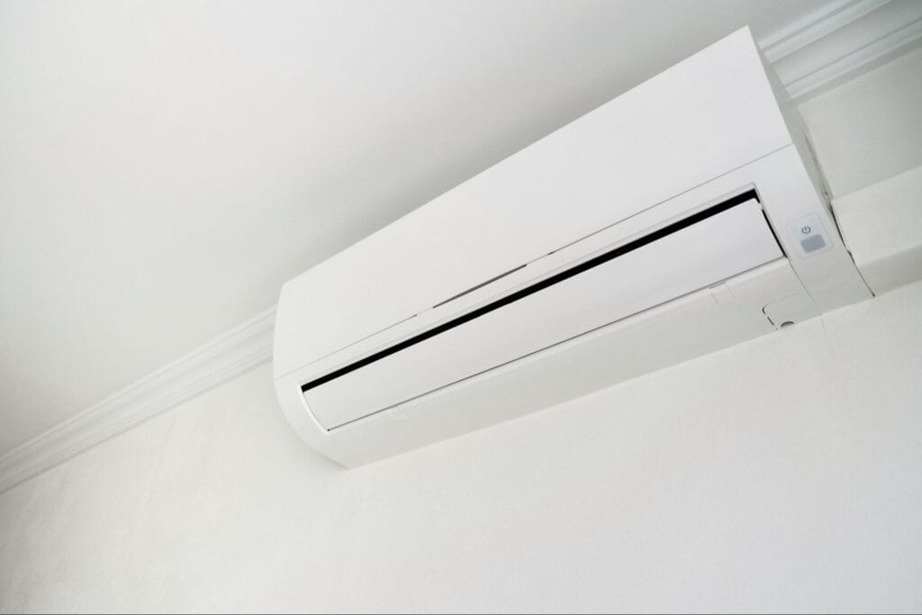 Close-up of a white ductless mini split indoor head with the air outlet louver and power button visible, showing the discharge vent and airflow path that need clean filters and clear space for efficient winter heating, serviced by S&P Heating in Clay Township, MI
