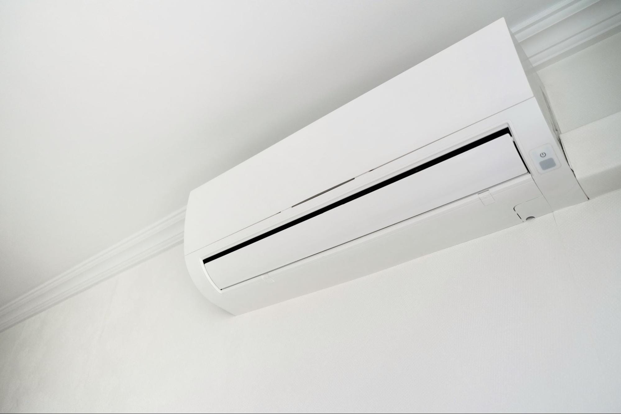 Close-up of a white ductless mini split indoor head with the air outlet louver and power button visible, showing the discharge vent and airflow path that need clean filters and clear space for efficient winter heating, serviced by S&P Heating in Clay Township, MI